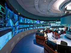 a large room with many monitors and people sitting at desks