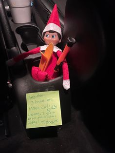 an elf is sitting in the back seat of a car with a note attached to it