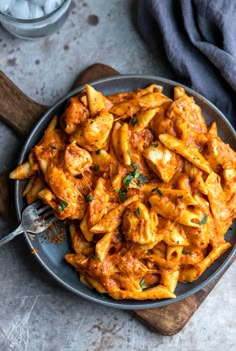 a plate filled with pasta and sauce on top of a wooden cutting board next to ice cubes