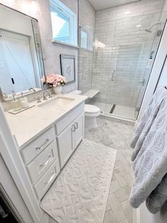 a bathroom with white cabinets and marble counter tops is pictured in this image, there are towels on the floor next to the shower