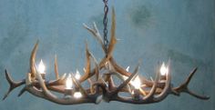 a chandelier with deer antlers hanging from it's sides and lit candles in the middle