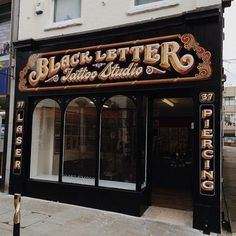 a black and gold storefront on the side of a building with windows that read, black letter salon studio