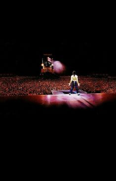 a man sitting on top of a stage in the middle of a crowd at a concert