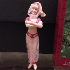 a figurine is standing next to a box with a christmas tree in the background