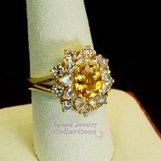 Thank you for coming in! This Vintage Ring has a strong striking yellow sapphire as its center piece. The sapphire is bezel set into a fancy setting with 8 heart and 8 round diamonds totaling 1.8 carats! Ring Size: 7.75 Total Weight: 9.58 grams Precious Metal: 18k solid gold Precious stones: -Yellow Sapphire: 2.92 carats, 9mm x 7.3mm -White Round Diamonds: 1.8 ct Hallmark: A18K Fine Yellow Oval Sapphire Ring, Fine Jewelry Sapphire Ring With Citrine Accent Stones, Yellow Sapphire Ring With Center Stone In Yellow Gold, Yellow Oval Sapphire Ring With Prong Setting, Yellow Oval Sapphire Diamond Ring, Oval Yellow Sapphire Ring With Diamonds, Formal Yellow Multi-stone Diamond Ring, Fine Jewelry Yellow Topaz Ring With Halo Setting, Exquisite Gold Multi-stone Sapphire Ring