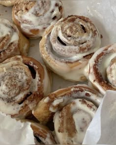 cinnamon rolls with icing sitting on top of white paper