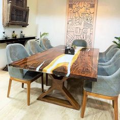 a dining room table with blue chairs and a large painting on the wall behind it