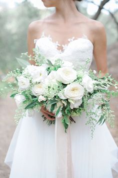 a bride holding a bouquet of white flowers