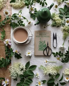 a cup of tea, scissors and flowers on a white tablecloth with the title british wildflowers