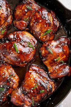 chicken thighs in a skillet with sesame seeds and seasoning sprinkled on top