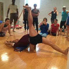 a group of people in a gym with one man doing a handstand on the floor