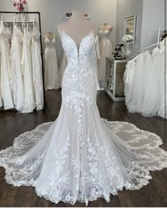 a white wedding dress is on display in a bridal room with other dresses and gowns