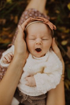 a woman holding a baby in her arms while she holds it's head up