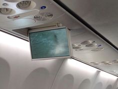 there is a tv hanging from the ceiling in an airplane with no people around it