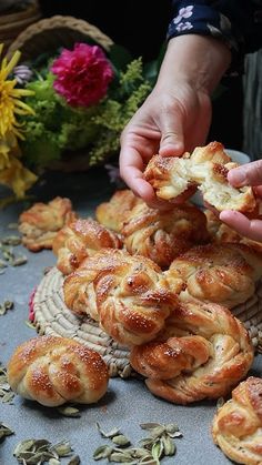 a person is picking up some bread from a wicker basket with flowers in the background