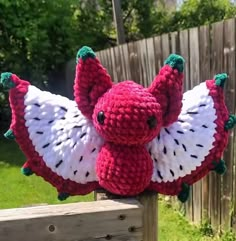 a crocheted stuffed animal hanging from a fence post