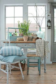 a room with some chairs and plants in the window sill on top of it