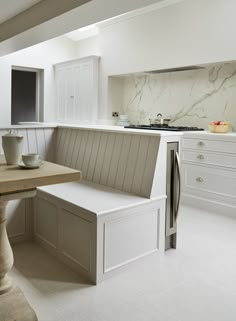 a kitchen with white cabinets and marble counter tops