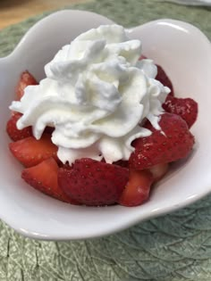 a white bowl filled with strawberries and whipped cream