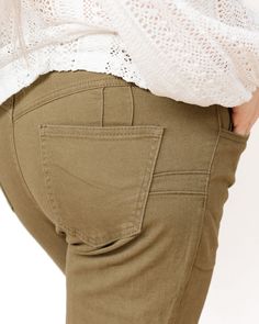 These pants are a stylish pair of mid-waisted jeans in an earthy olive green color. They feature a classic design with a modern twist, making them a versatile addition to any wardrobe. These pants are tailored to provide a flattering fit, with a high-rise waist that accentuates the wearer's natural waistline, creating a sleek and elongated silhouette. The front of the pants includes a traditional button and zipper closure, adding to their classic appeal. The trousers are equipped with functional front and back pockets, enhancing their practicality without compromising on style. The fabric appears to be a comfortable and durable material, suitable for both casual and more polished looks. One of the standout features of these pants is their wide-leg cut, which adds a touch of retro flair and Mid Waist Jeans, Olive Green Color, Polished Look, Flare Jeans, Green Color, Best Sellers, Olive Green, Classic Design, High Rise