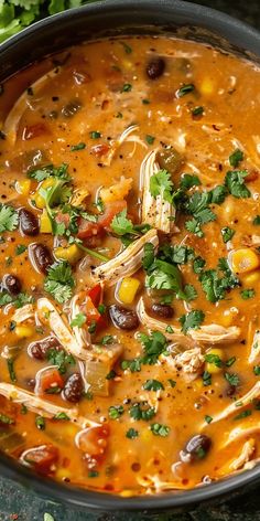 a bowl filled with soup and garnished with cilantro, black olives, corn