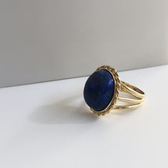 Lapis lazuli - richly blue and in excellent shape. This massive lapis is held in a beautiful vintage ring crafted in 18K yellow gold with beautiful braided bezel detail. The shank splits in three different bands tapering down to a single band at the bottom of 4.30mm This ring is currently a size 8.5 but can be sized down upon request. With any pre-owned/Vintage/Antique items, it is common to have some wear, As we inspect each piece of our jewelry, we make sure the wear and tear is acceptable wit Elegant Blue Oval Cabochon Signet Ring, Blue Cabochon Sapphire Ring In 14k Gold, Elegant Blue Gemstone Dome Ring, Classic Blue Lapis Lazuli Rings, Timeless Blue Gemstone Signet Ring, Blue 14k Gold Oval Cabochon Rings, 14k Gold Blue Oval Cabochon Rings, Elegant Lapis Lazuli Ring Jewelry, Oval Blue Lapis Lazuli Rings