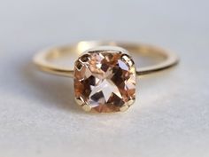 an orange diamond is sitting on top of a white surface and it's yellow gold band