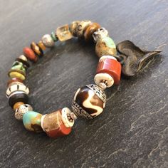 "Boho at its best!   This bracelet is perfect to wear with your Fall neutrals.. cream sweater and jeans, leather boots, a great dress as the weather gets cooler and into the holidays..  It is designed around a gorgeous Nepali Silver capped Horn bead from Tibet.  This is combined with a rustic eclectic Fall mix of beads and stones including Ostrich Shell, Red Jasper, Genuine Hubei Turquoise, carved bone beads, faceted Citrine and a silver rimmed ebony wheel.  An artisan blackened bronze rustic he