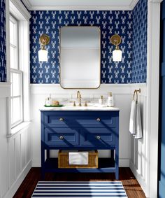 a bathroom with blue and white wallpaper, wooden flooring and a large mirror above the sink