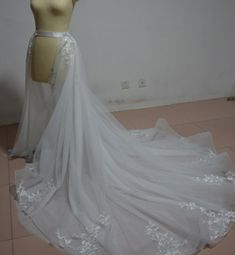 a white wedding dress on a mannequin in front of a wall and floor