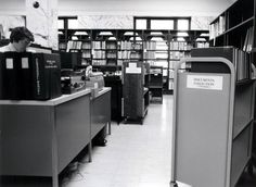 an old photo of a library with bookshelves and people working on computers in it