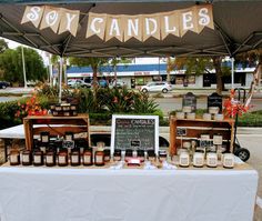 an outdoor market with candles on display under a sign that says soy candle's