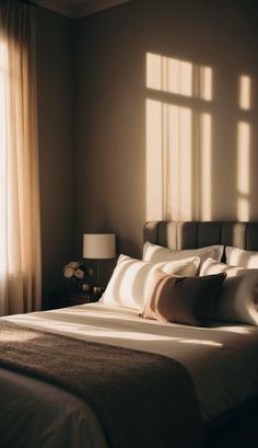 a bed sitting in a bedroom next to a window with sunlight coming through the windows