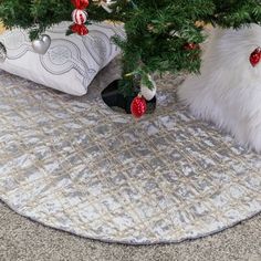 a christmas tree with ornaments on it in front of a white pillow and other decorations