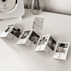 an open photo album sitting on top of a table next to a clock and vase