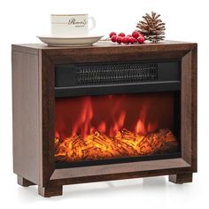 an electric fireplace heater with red flames and pine cones on the top, next to a white mug