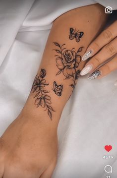 a woman's arm with flowers and butterflies tattooed on the side of her wrist