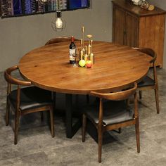 a round wooden table with four chairs around it and bottles of wine on the table