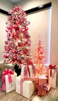 a christmas tree is decorated with pink and red ribbons, bows, and other presents