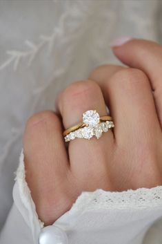 a woman's hand with a gold and white engagement ring on her left hand