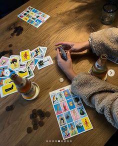 a person sitting at a table with some cards on it and a bottle of beer