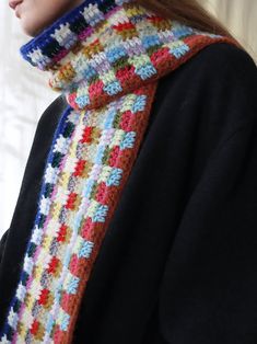 a woman wearing a multicolored crocheted scarf