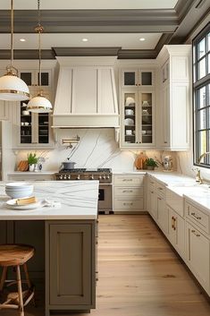 a large kitchen with white cabinets and wooden flooring, along with an island in the middle