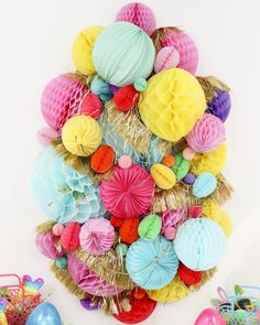 a bunch of balloons and decorations on a white wall with some straw in the middle