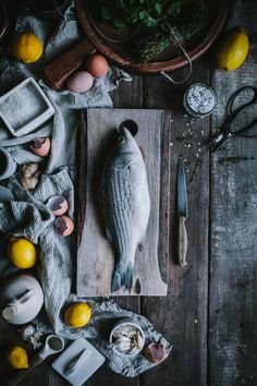 an assortment of food on a cutting board with lemons, eggs and other items