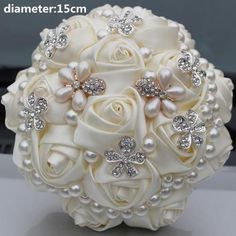 a bridal bouquet with white roses and pearls on it's side, sitting on top of a table