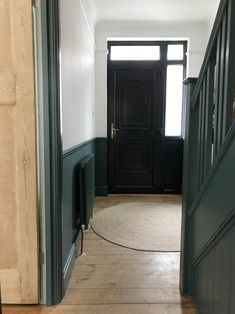 an empty hallway with dark green doors and wooden floors is pictured in this image taken from the entryway