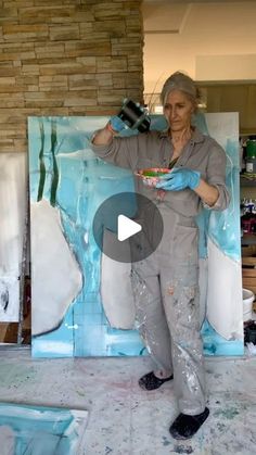 a woman in grey shirt and blue gloves painting a wall