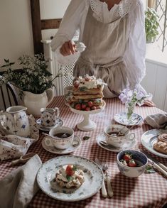 a woman sitting at a table covered in plates and cups with food on them,