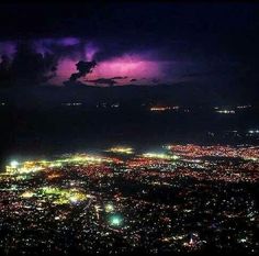 an aerial view of the city lights and clouds at night from a high altitude plane